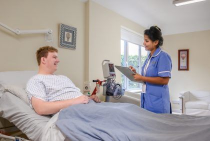 A nurse talks with a patient in their private room